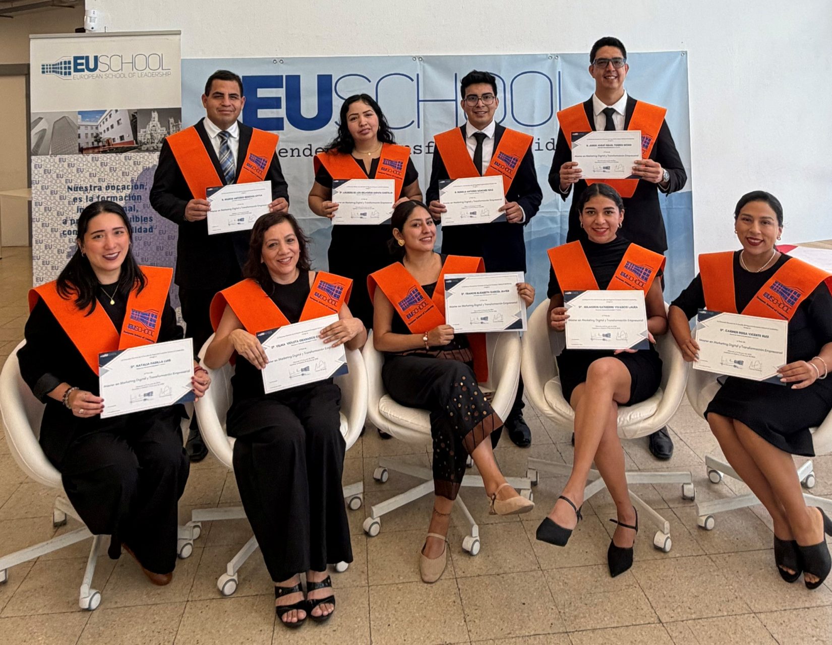 Alumnos de EUschool mostrando sus diplomas con becas naranjas de graduación